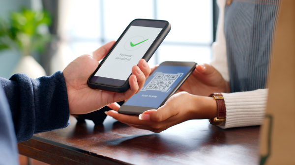 Celular apontando para máquina de pagamento e fazendo a leitura de um QRCode para transação via conta digital.